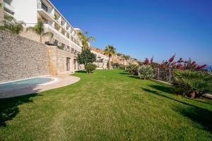 une cour herbeuse à côté d'un bâtiment avec piscine dans l'établissement Cape Krio Boutique Hotel & SPA - Over 9 years old Adult Only, à Datça