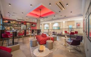 a lobby with a bar with red chairs and tables at Promotel in Carros