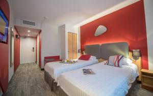 a hotel room with two beds and a red wall at Promotel in Carros
