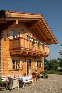 a wooden house with a balcony and a table and chairs at Alchemilla in Bad Feilnbach