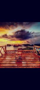 un banco sentado en un muelle de madera con una puesta de sol en Arrys Watukarung Surfcamp en Kalak