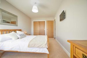 a bedroom with a white bed and a flat screen tv at Host & Stay - Sunflower Cottage in Seahouses