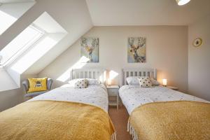 ein Schlafzimmer im Dachgeschoss mit zwei Betten und einem Fenster in der Unterkunft Host & Stay - Sunflower Cottage in Seahouses