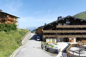 a building on a mountain with a road next to it at Résidence Roc De Tougne in Méribel