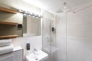 a white bathroom with a shower and a sink at Munich Rooms Hotel in Munich