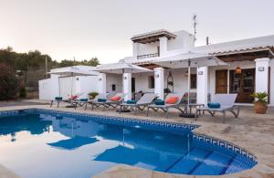 a villa with a swimming pool with chairs and umbrellas at Villa Los Naranjos in Cala Llonga