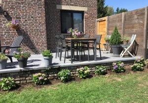 a patio with a table and chairs and flowers at Villa van Brienen - Studio in Dilsen-Stokkem