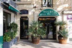 a hotel with potted plants in front of a building at Le Grand Albert 1er in Maisons-Alfort
