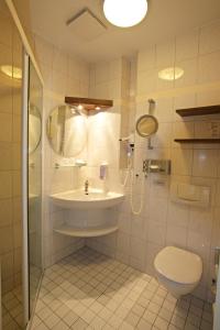uma casa de banho com um lavatório, um chuveiro e um WC. em Panorama Hotel Lohme em Lohme