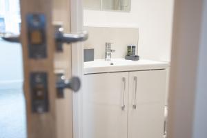 a white bathroom sink next to a door at Luxury Boutique Harbour Apartments - Heart of Torquay - Near Babbacoombe & Beach by Belvilla in Torquay