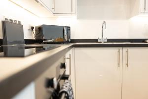a kitchen with a sink and a microwave at Luxury Boutique Harbour Apartments - Heart of Torquay - Near Babbacoombe & Beach in Torquay