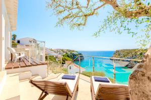 Un balcón con sillas y vistas al océano. en Seafront Villa Bellavista with heated pool, en Cala'n Porter