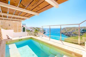 a villa with a swimming pool and a view of the ocean at Seafront Villa Bellavista with heated pool in Cala en Porter