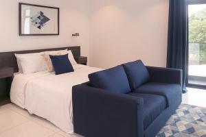 1 dormitorio con 1 cama y 1 silla azul en Embassy Gardens Luxury Apartments, en Accra