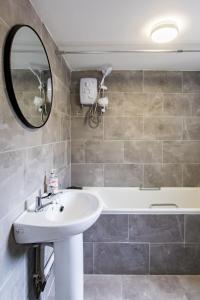 uma casa de banho com um lavatório, uma banheira e um espelho. em FREE PARKING -2 Bed Apartment, 7mins to City Centre - by StirkMartin em Cardiff