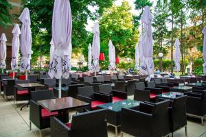 a row of tables and chairs with white umbrellas at Hotel Srbija-FREE PARKING in Belgrade