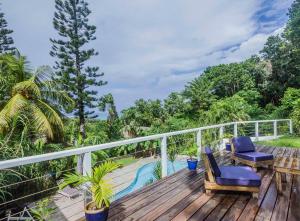 a wooden deck with two chairs and a swimming pool at Carre Royal in Deshaies