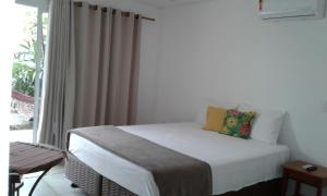 małe łóżko w pokoju z oknem w obiekcie Pontal Flats w mieście Paraty