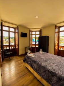 a bedroom with a bed and a television and windows at Casona Hotel in Pasto