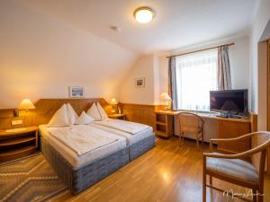 a hotel room with a bed and a desk and a television at Pension Ehrenfried - Hotel garni in Kindberg