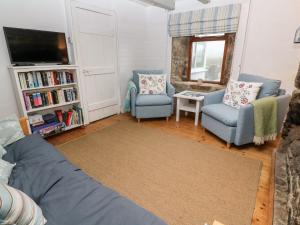 uma sala de estar com duas cadeiras e uma televisão em Miners Cottage em Penzance