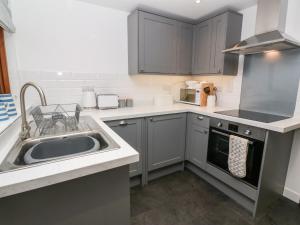 uma cozinha com armários cinzentos e um lavatório em Miners Cottage em Penzance
