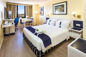 um quarto de hotel com uma cama grande e uma secretária em Holiday Inn Lisbon, an IHG Hotel em Lisboa