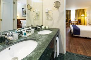a hotel bathroom with two sinks and a bed at Holiday Inn Lisbon by IHG in Lisbon