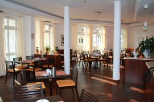 un comedor con mesas, sillas y ventanas en Stadthotel Berggeist en Penzberg