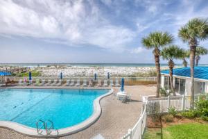 a swimming pool with palm trees and the beach at Sea Oats in Fort Walton Beach