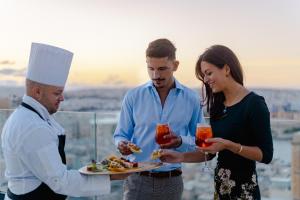 a man and a woman holding a plate of food at The Embassy Valletta Hotel in Valletta