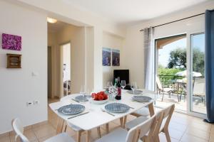 un comedor blanco con una mesa y sillas blancas en Villa Renata, en Barbati