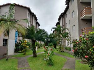 a courtyard of a building with palm trees and flowers at Condomínio Villagio de Maranduba VII - Praia do Sapê in Ubatuba