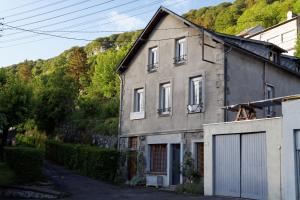 une maison ancienne avec un garage en face d'une montagne dans l'établissement Villa Jean Julien - Le Capucin - Appartement T1 - 1 chambres - 4 personnes, à Le Mont-Dore