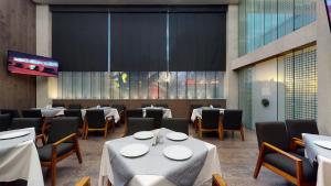 a dining room with tables and chairs and a tv at Hotel Patriotismo in Mexico City