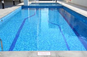 a large blue swimming pool with a sign in it at The Lodge Suites in Manama
