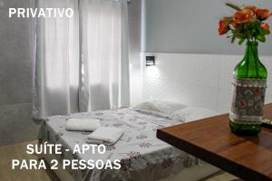 1 dormitorio con 1 cama con mesa y un jarrón de flores en Disponivel Virada - Estúdios e suítes com piscina, ar, wifi e estacionamento 6X no cartão sem juros, en Porto Belo