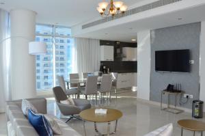 The Lodge Suites في المنامة: غرفة معيشة مع أريكة وغرفة طعام