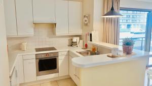 a kitchen with white cabinets and a sink at Ruim, lichtrijk appartement met groot terras uitstekend gelegen in De Panne in De Panne