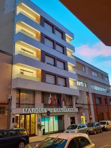 un edificio con coches estacionados frente a él en Hotel Marqués de Santillana, en Torrelavega