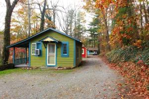 une petite maison verte et bleue dans les bois dans l'établissement The Pines Cottages, à Asheville