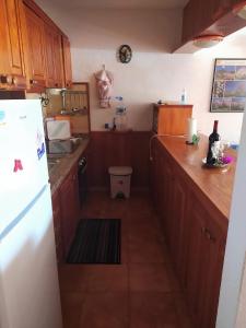 uma cozinha com armários de madeira e um frigorífico branco em Apartamento Neptuno playa 06 em Puerto de Santiago