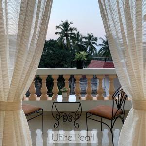 Marmagao的住宿－Vistara By The Beach Goa，阳台配有两把椅子和一张带窗帘的桌子