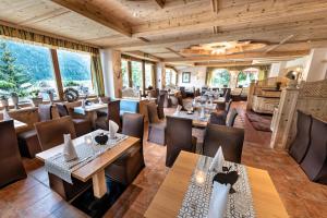 un ristorante con soffitti e tavoli in legno e sedie di Das Posthaus stubai&smart Hotel a Fulpmes
