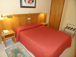 a small bedroom with a red bed and a table at Hotel Rey Arturo Burgos in Villagonzalo-Pedernales