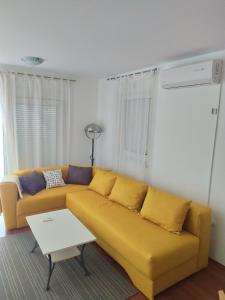 ein gelbes Sofa im Wohnzimmer mit einem Tisch in der Unterkunft Zobić Family Apartments in Rab