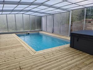 an indoor swimming pool with a pergola and a wooden deck at Gîte Le Lijaly in Bournezeau