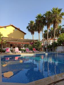 a large swimming pool with chairs and palm trees at Işıl Suit Apart Otel in Dalyan