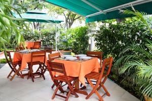 un patio con mesa, sillas y sombrilla en Hotel Imbanaco, en Cali