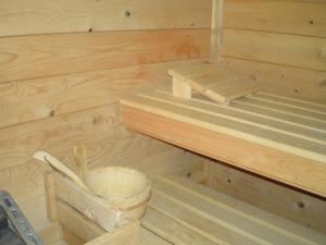 a wooden sauna with a bench and a bucket at B&B Zeespiegel in Zandvoort